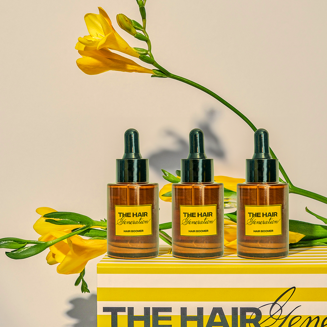 Three bottles of 'The Hair Generation' with yellow flowers on a beige background