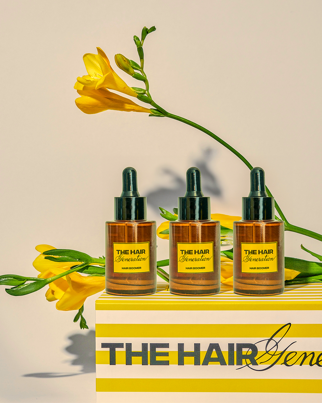 Three bottles of 'The Hair Generation' with yellow flowers on a beige background