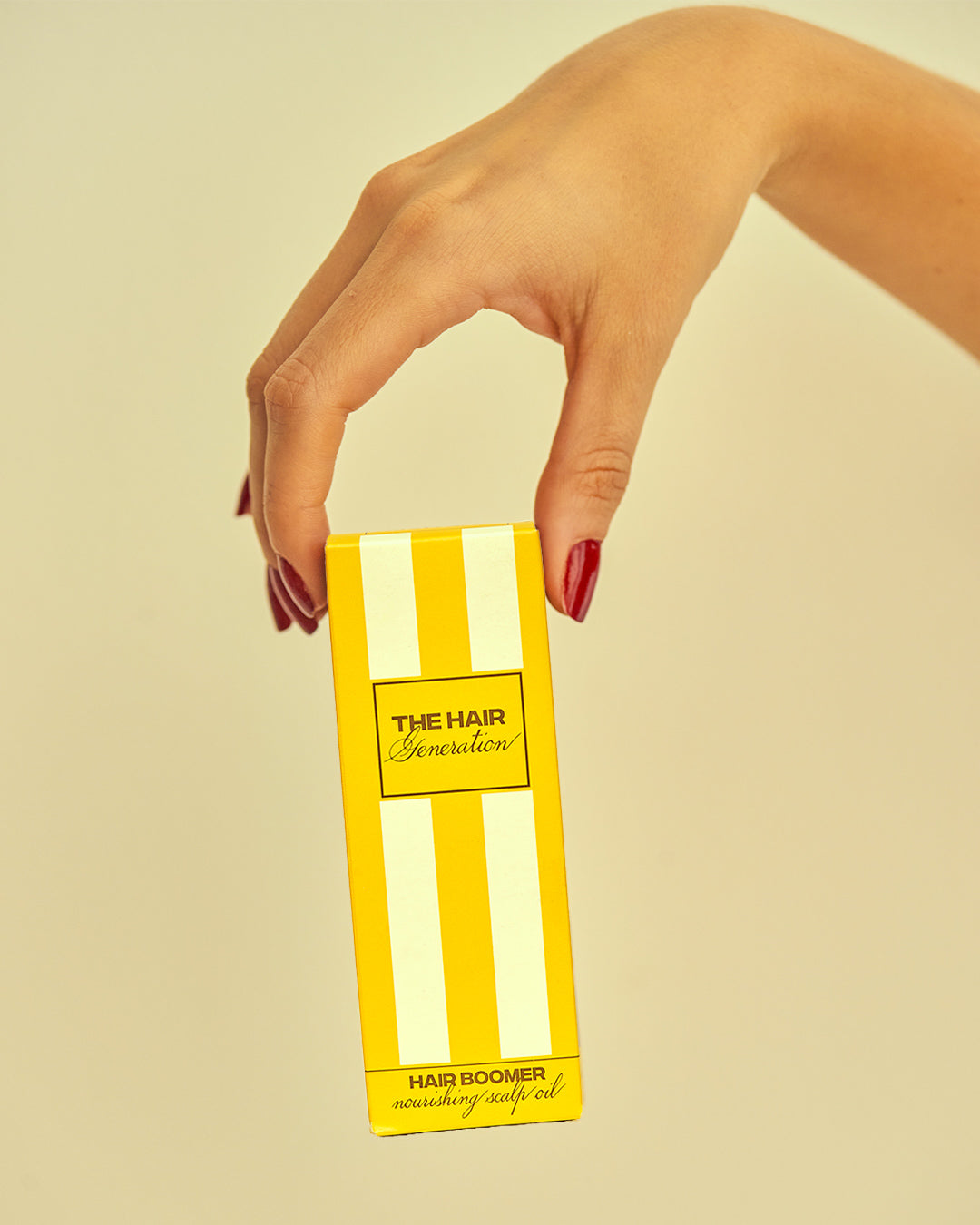Hand holding a yellow box with 'The Hair Generation' branding on a beige background