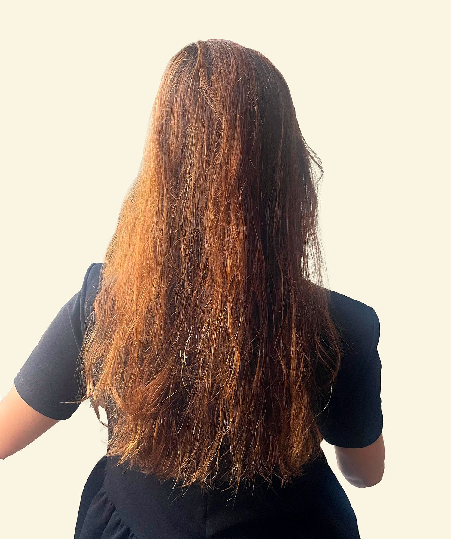 Person with long, wavy hair standing against a plain background